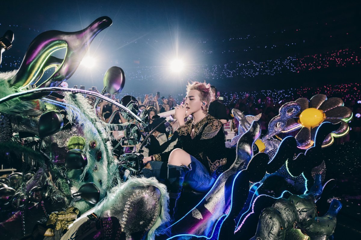 G-DRAGON performing at Osaka Kyocera Dome, surrounded by daisies.